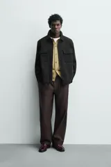 Sobrecamisa relaxed fit color beige con tejido elástico, cuello solapa, manga larga con puños abotonados, bolsillos de plastrón con solapa en el pecho, bolsillos laterales de vivo en la cadera y cierre frontal de botones.
