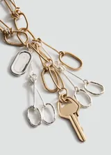 Collar de diseño metálico con cadenas combinadas en tonos dorados y plateados, con múltiples dijes colgantes que incluyen una llave y eslabones decorativos.