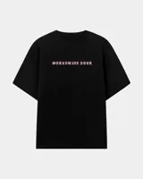 Remera oversize negra con cuello redondo, mangas cortas y estampa frontal con la leyenda "Worldwide Tour" en color rosa.