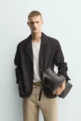Blazer de corte relajado confeccionada en piel con acabado de ante. Presenta cuello con solapas de muesca, cierre frontal de dos botones, mangas largas y bolsillos de plastrón en la parte delantera. Destaca por sus costuras con efecto lavado que le otorgan un aspecto vintage.