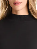 Buzo de punto color beige, con cuello alto y manga larga. Presenta un diseño de tejido liso con detalle de canalé en los hombros y puños.