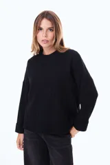 Buzo tejido de punto acanalado en color bordó, con cuello alto y mangas largas anchas con puños ajustados.