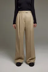 Pantalón sastrero color beige de lana, con tiro medio, corte amplio, cintura cruzada, pinzas, bolsillos delanteros y traseros, cierre a tono, botón interno y gancho pantalonero.