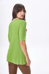 Remera negra de tejido de punto acanalado, con cuello redondo y mangas cortas. Presenta un tajo lateral pronunciado.