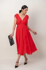 Vestido largo rojo de corte griego, sin mangas, con escote en V profundo, falda amplia y detalles de encaje.