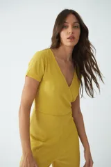 Monoprenda larga de textura acanalada, color mostaza, con escote en V cruzado y mangas cortas.