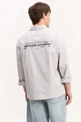 Camisa de manga larga con diseño a rayas verticales en color verde y blanco, cuello clásico y estampa con bordado en la espalda con la frase "Expect Nothing, appreciate everything".