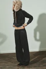 Pantalón de tiro medio con cintura elástica, confeccionado en mezcla de algodón con efecto lavado oscuro. Presenta un corte ancho y voluminoso, con paneles curvos cosidos en los laterales de las piernas.