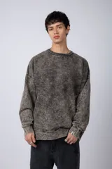 Buzo de cuello redondo con efecto de teñido artesanal acid wash. Presenta un corte oversize, mangas largas con puños acanalados y etiqueta pequeña en el puño izquierdo.