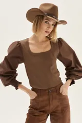 Top de calce ajustado color marrón, con escote cuadrado y mangas largas abullonadas de tela lisa. Los puños de las mangas son elastizados.