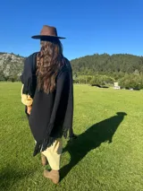 Ruana de lana merino en color tostado, con diseño de punto texturizado y terminación de flecos en el ruedo.