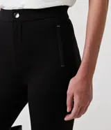 Pantalón legging negro de viscosa con elastano, corte cigarrillo, con cierre y detalles en material sintético.