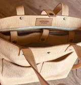 Bolso tipo tote de cuero sintético color beige con textura tipo cocodrilo. Tiene doble asa de mano y correa larga extraíble y ajustable. Cuenta con cierre principal, dos bolsillos externos y un bolsillo interno con cierre.