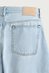 Jeans de corte barrel fit confeccionados en denim de algodón rígido, con diseño de cinco bolsillos y cierre frontal con botones. Presentan un lavado claro con efecto de roturas en las perneras.