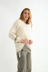 Buzo de tejido de punto con textura suave, color celeste pastel con efecto jaspeado. Presenta cuello redondo, mangas largas con terminación en puño y un diseño de canalé en la parte superior del pecho.
