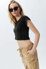 Top corto de manga corta, color negro con efecto desgastado o acid wash, cuello redondo y costuras verticales que definen la silueta.