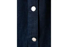 Mono largo de denim color azul oscuro, con cuello redondo, cierre frontal con botones metálicos, mangas largas y corte recto en las piernas.