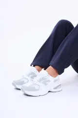 Championes casuales de diseño chunky en color blanco con detalles en gris, confeccionados en poliuretano y malla transpirable, con suela gruesa y cordones tono sobre tono.