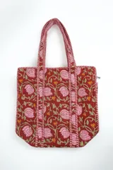 Bolso tipo tote acolchado, con diseño estampado de flores y tallos sobre fondo bordó, y asas con detalles a rayas.