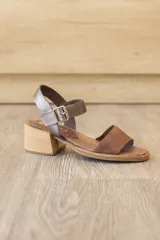 Sandalia de cuero marrón con tira frontal en cuero y correa al tobillo metalizada con hebilla ajustable. Cuenta con tacón ancho y bajo de acabado símil madera.