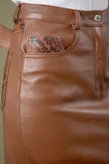 Pollera midi de cuero ovino con diseño tipo jean, cierre frontal con botón y tajo central.