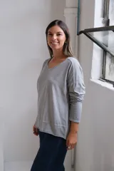 Remera de algodón gris con cuello en V, mangas largas y corte holgado con ruedo asimétrico.