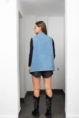 Chaleco de jean largo con corte oversize, cierre frontal con botones metálicos, bolsillos laterales y bolsillos superiores con solapa.