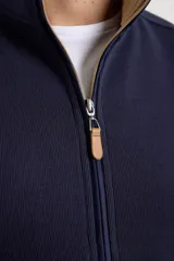 Cardigan de tejido de punto color verde militar, con cierre frontal de metal y cuello redondo. Presenta detalle de tejido plano en la cartera del cierre y en los bolsillos laterales.