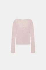 Chaqueta de punto de algodón con escote en pico y manga larga, que incluye un top interior integrado con detalle de encaje a tono. Presenta cierre frontal con botones.