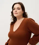 Vestido midi de punto acanalado color marrón, con escote en V y mangas largas abullonadas. Presenta un diseño ajustado en el torso que se ensancha suavemente hacia el ruedo.