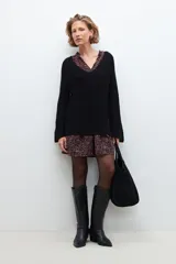 Sweater negro de tejido de punto grueso, con escote en V y detalle de cinta estampada floral en el borde del escote.