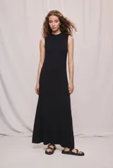 Vestido largo negro de tejido fluido, con corte evasé, sin mangas y cuello redondo. Silueta entallada en la parte superior que se amplía suavemente hacia el ruedo.