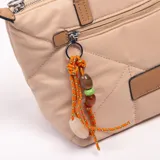 Bandolera tipo shopper color caqui, con diseño acolchado y pespuntes geométricos. Tiene doble asa de mano en tono marrón, bolsillo frontal con cierre y un charm colgante decorativo de cordones y cuentas. Incluye correa ajustable y desmontable.