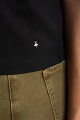 Remera negra de algodón con mangas cortas abullonadas que presentan detalles de encaje bordado y calado en los extremos.