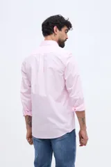 Camisa de manga larga color rosado, con cuello abotonado, cierre frontal de botones y un bolsillo ojal en el pecho.