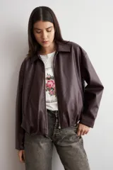 Chaqueta bomber de eco cuero en color bordó, con cierre frontal metálico y cuello clásico. Presenta un diseño de corte recto y mangas largas.