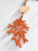 Collar largo con tiras de cuero marrón, dije principal en forma de coral de resina naranja y aplique ovalado superior nacarado.