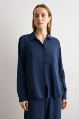 Camisa de corte clásico y calce holgado, con cuello camisero, cierre frontal de botones y mangas largas con puños abotonados.