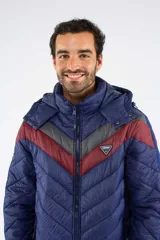 Campera puffer Mistral con capucha desmontable, diseño capitoneado y patrón chevron en el pecho en tonos azul marino, bordó y gris. Cuenta con cierre frontal, bolsillos laterales con cierre y logo de la marca aplicado en el pecho.