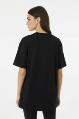 Remera de algodón de manga corta y cuello redondo, con diseño holgado y estampado frontal con motivos florales y texto.