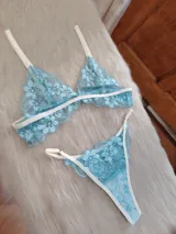 Conjunto de lencería compuesto por un corpiño triangular y una bombacha, confeccionados en encaje floral color aguamarina con detalles de ribetes en color champagne. El corpiño cuenta con breteles regulables y la bombacha presenta laterales ajustables.