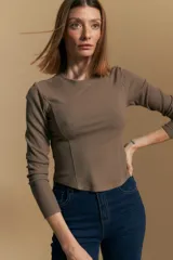 Remera blanca de manga larga con tejido acanalado, cuello redondo y corte ajustado al cuerpo. Presenta costuras verticales que definen la silueta.