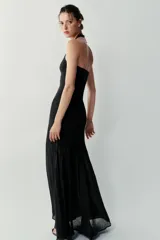 Vestido largo negro de cuello halter, espalda descubierta y escote redondo. Presenta un diseño de punto combinado en la parte superior y una falda larga de tejido fluido.