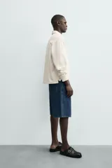 Polo de manga larga color crema, confeccionado en tejido de algodón, con cuello solapa y cierre frontal de botonadura. Presenta un calce relajado y acabados en rib en puños y ruedo.