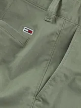 Pantalón corto tipo cargo de corte slim, confeccionado en algodón elástico. Presenta bolsillos laterales tipo cargo, bolsillos laterales ribeteados y bolsillos traseros de ojal. Incluye cierre de cremallera con botón y detalles distintivos de la marca Tommy Jeans.