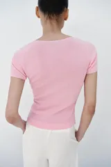 Top de punto color rosado, con cuello en V, manga corta y detalle de frunces delanteros con ribetes a contraste.