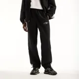 Pantalón New Balance de hombre, modelo Trackside, color negro con detalles laterales grises y logo impreso en la pierna. Cuenta con cintura elástica y diseño deportivo.