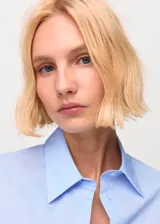 Camisa de popelina celeste, de silueta slim, manga larga y cuello camisero.
