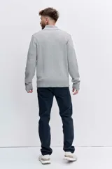 Cardigan de punto color azul marino, con cierre frontal completo, cuello alto y puños acanalados. Presenta un pequeño bordado distintivo en el pecho.