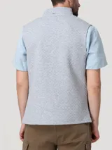 Chaleco gris melange con textura acolchada de rombos, cuello alto y cierre frontal de cremallera. Presenta un pequeño parche bordado con silueta de pato en el pecho.